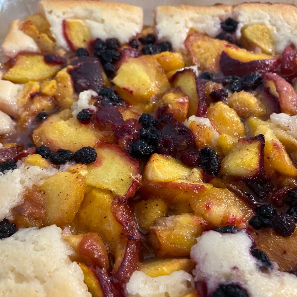 Juicy peach cobbler with golden topping, served warm in the baking dish.