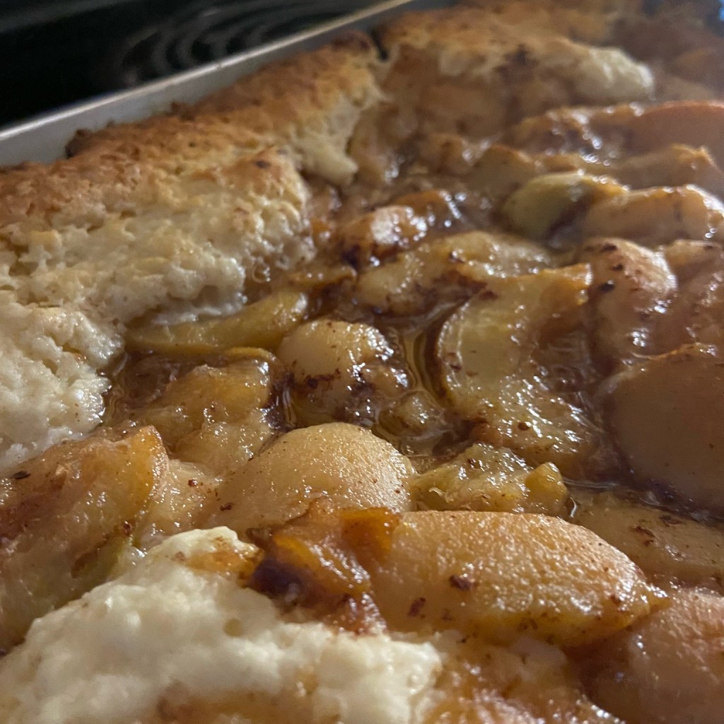 Freshly baked peach cobbler in the pan with golden brown topping.